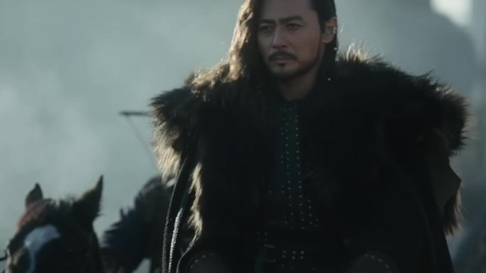 Jang Dong Gun como Ta-gon, de manto de pele escura, montado a cavalo, em quadro do trailer oficial de Arthdal Chronicles