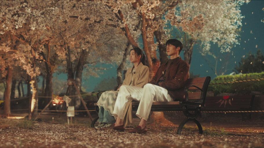 Ahn Eun-jin e Jang Ki-yong sentados sob árvores em imagem promocional