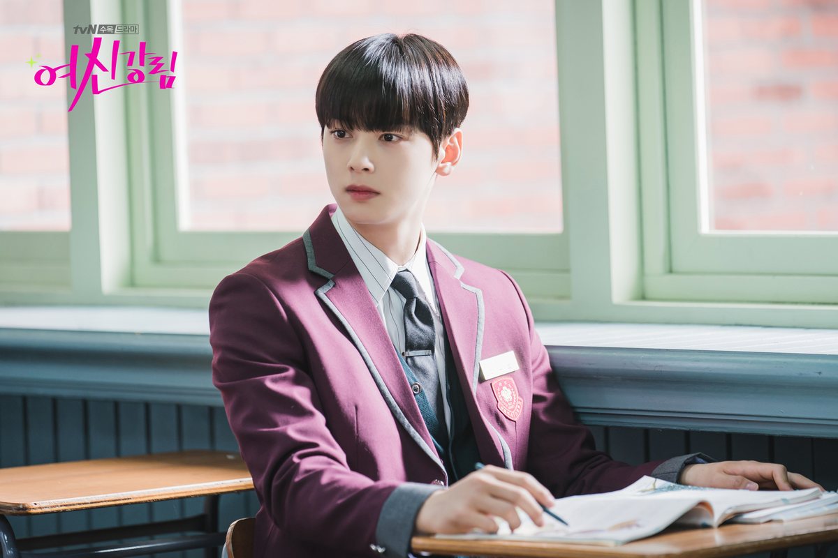 Cha Eun-woo como Su-ho, de uniforme vinho e gravata cinza, sentado numa carteira perto da janela com caneta e livro aberto