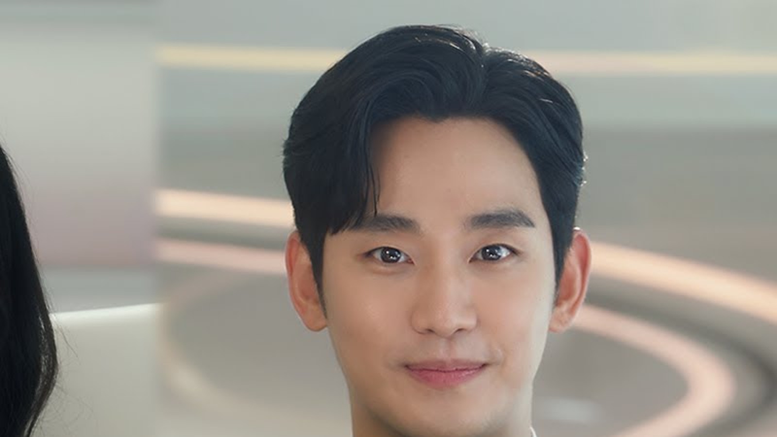 Kim Soo-hyun sorrindo de terno escuro em cena de Rainha das Lágrimas