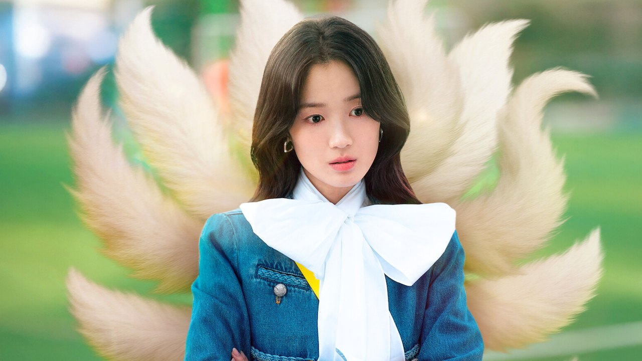 Kim Hye-yoon de jaqueta jeans e laço branco no pescoço, com nove caudas claras de raposa abertas atrás dela, diante de um fundo verde desfocado