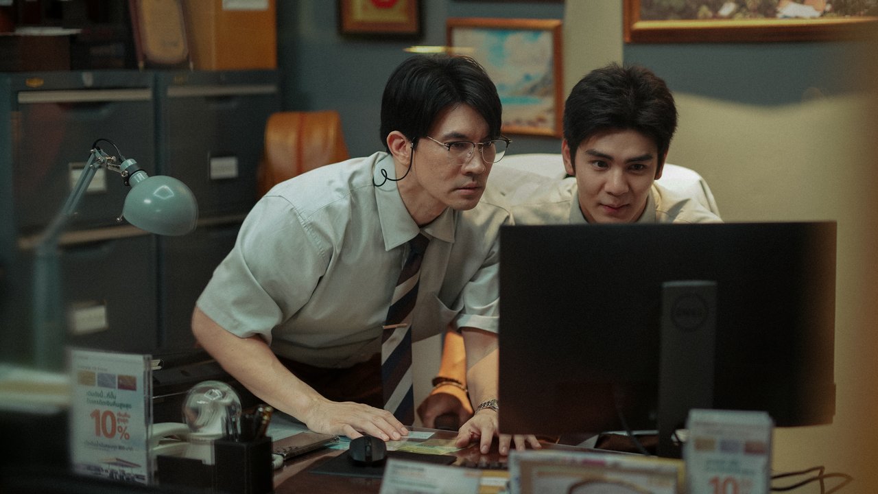 Dois homens de camisa social e gravata olham juntos para a tela de um computador numa mesa de escritório