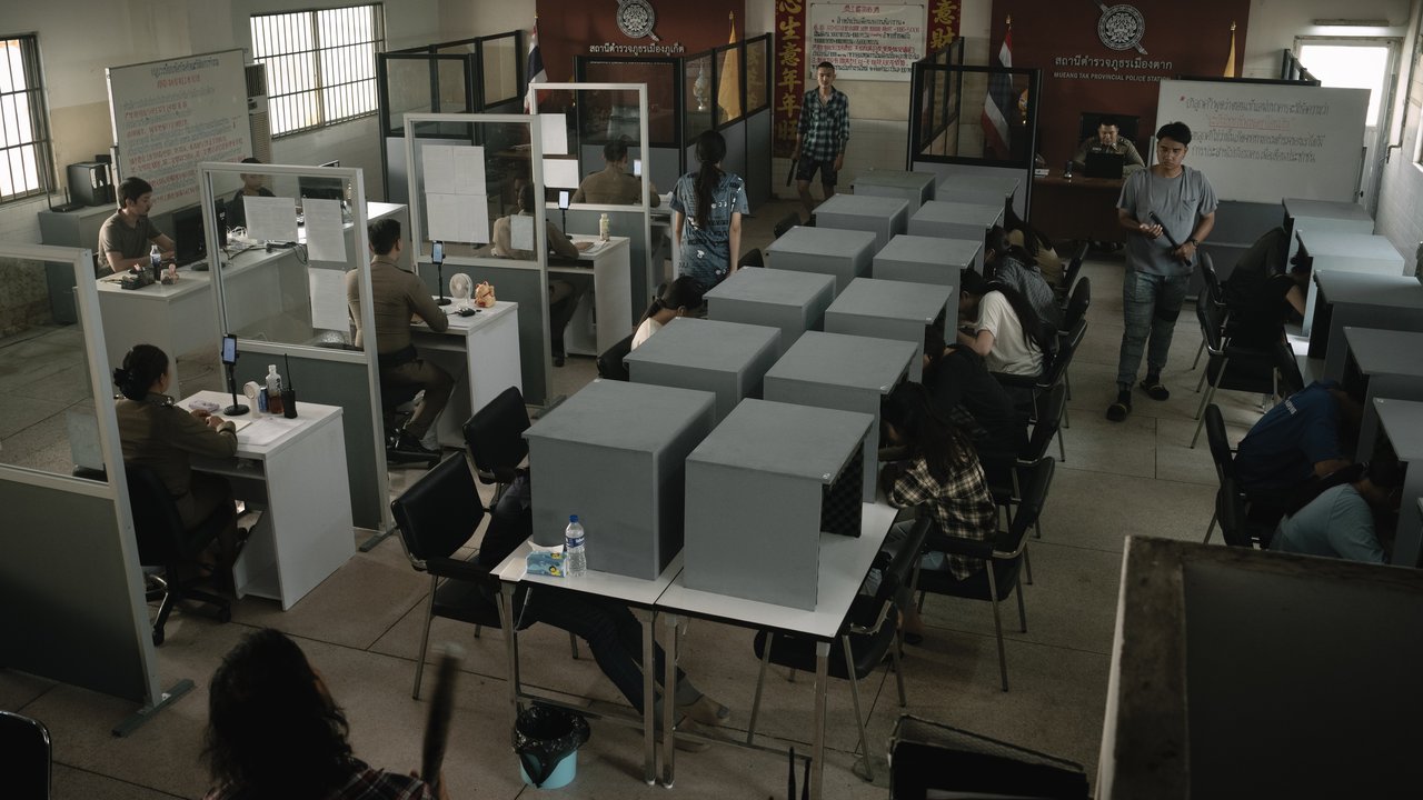 Sala ampla com fileiras de cabines cinzentas e pessoas sentadas trabalhando em mesas