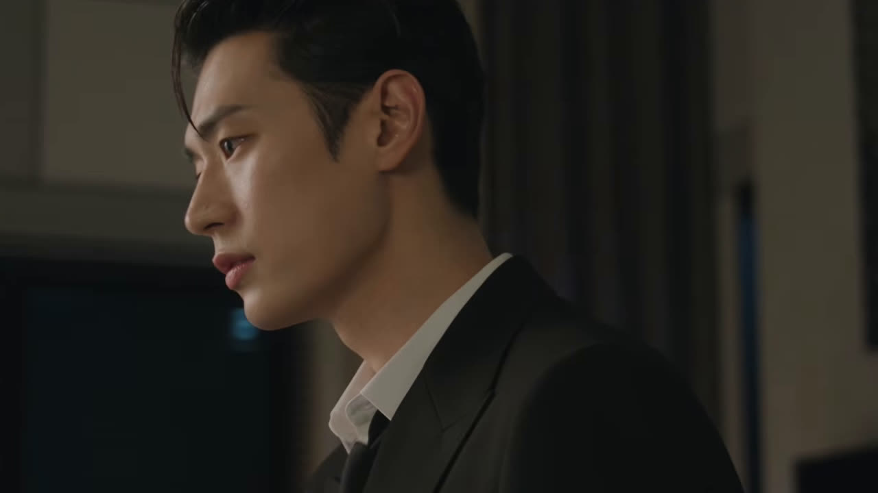 Park Seo Ham de perfil, de terno escuro e camisa branca, em quadro do vídeo oficial de Dive into You