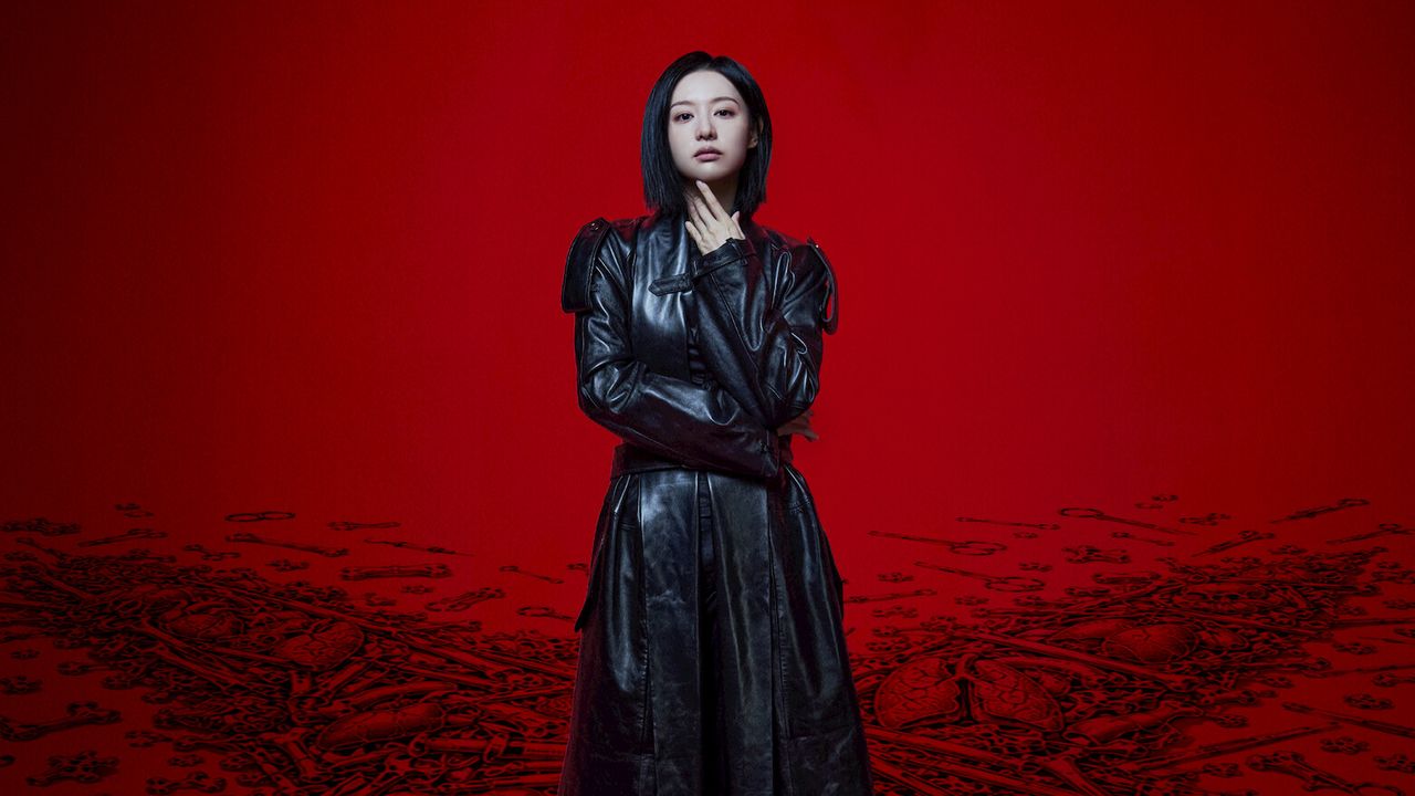 Kim Ji-won como a cirurgiã Gye Su-jeong, de casaco de couro preto e cabelo curto, em pé sobre fundo vermelho em imagem de divulgação de Doctor X