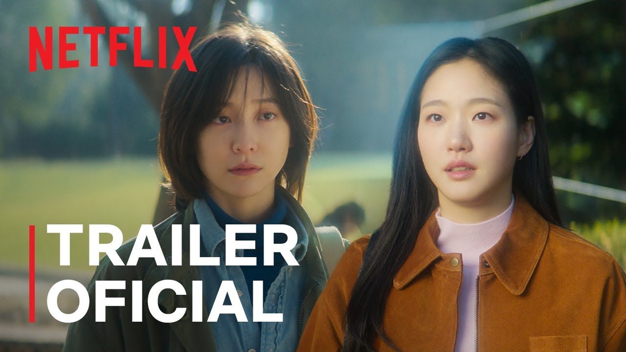As protagonistas Kim Go-eun e Park Ji-hyun lado a lado numa rua arborizada, uma de cabelo curto e jaqueta escura e outra de jaqueta marrom, com a marca Netflix e a inscrição Trailer oficial