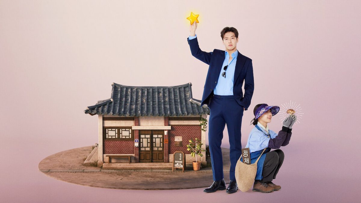 Kang Ha-neul de terno azul-marinho erguendo uma estrela dourada ao lado de uma pequena casa tradicional coreana, com Ko Min-si agachada de viseira segurando um cogumelo