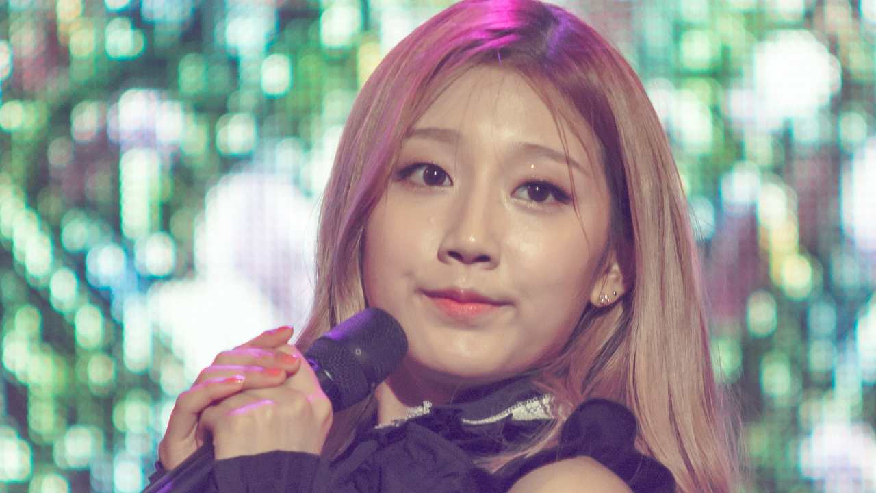 Jeong Yein em show do Lovelyz em 2016, de cabelo loiro rosado, segurando um microfone junto ao rosto