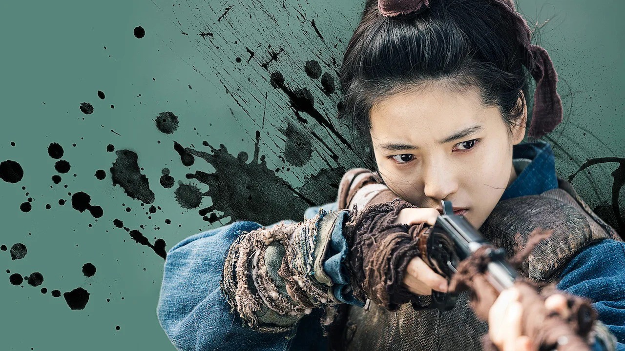Kim Tae Ri como Go Ae-sin, de cabelo preso e roupa azul gasta, mirando um fuzil, sobre fundo verde com respingos de tinta preta
