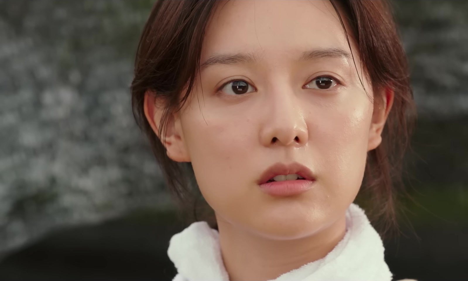 Close de Kim Ji-won, de cabelo preso e toalha branca no pescoço, olhando para o lado com expressão séria, em cena do trailer de My Liberation Notes