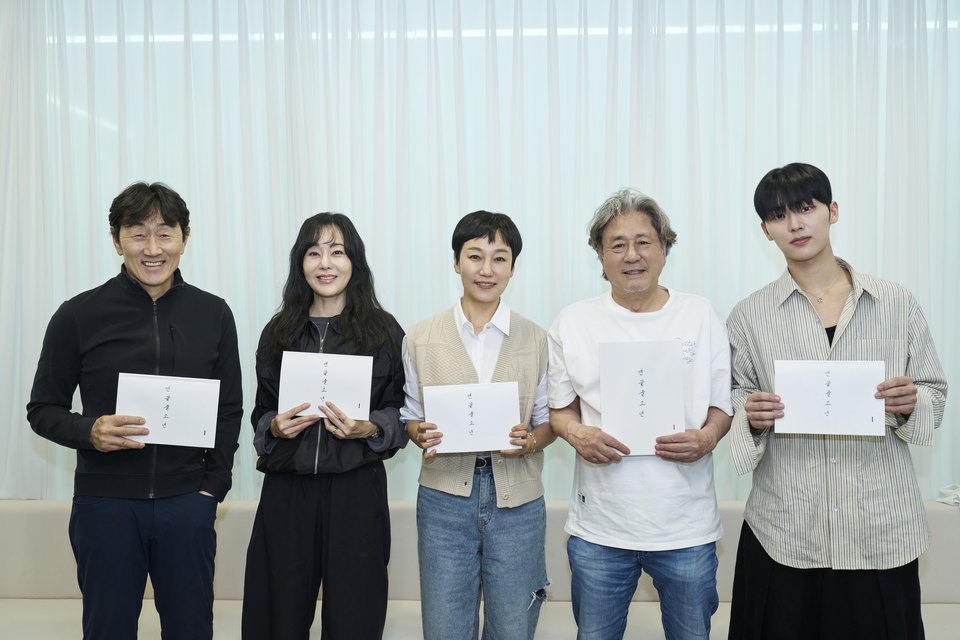 Cinco atores em pé diante de uma cortina branca, cada um segurando um roteiro, com Choi Min-sik de cabelo grisalho e Choi Hyun-wook de camisa listrada à direita