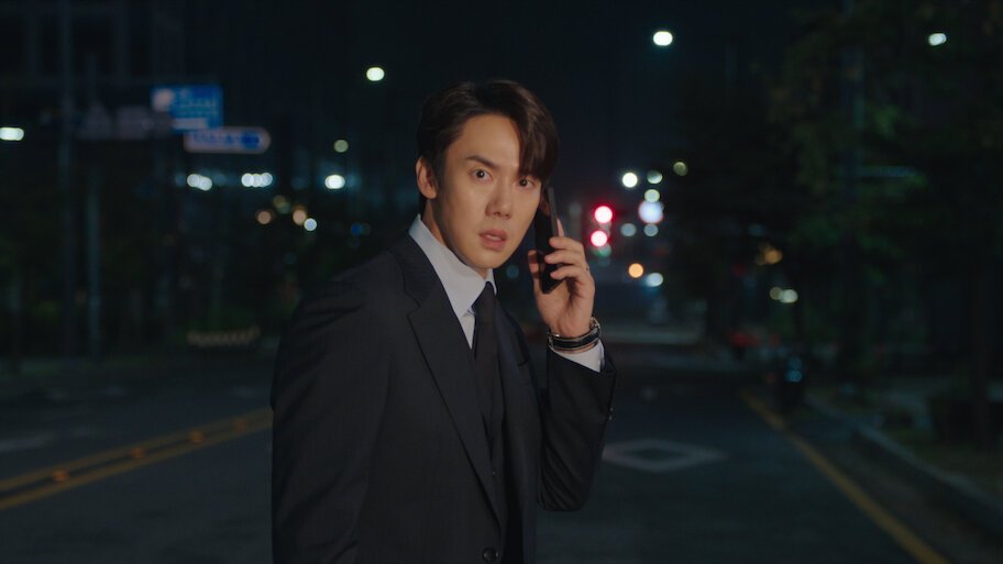 Yoo Yeon-seok de terno atende telefone numa rua à noite