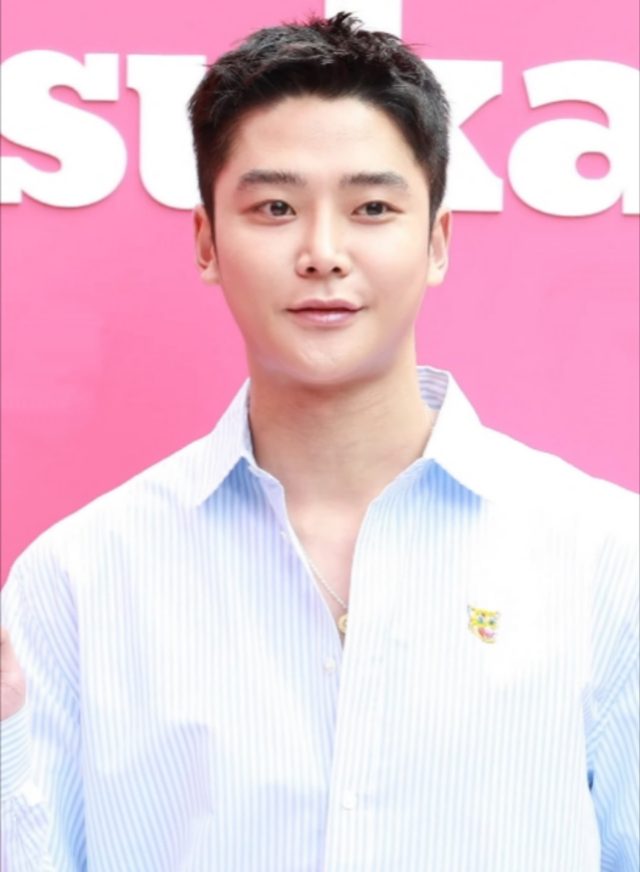 Rowoon de camisa listrada azul e branca diante de painel rosa