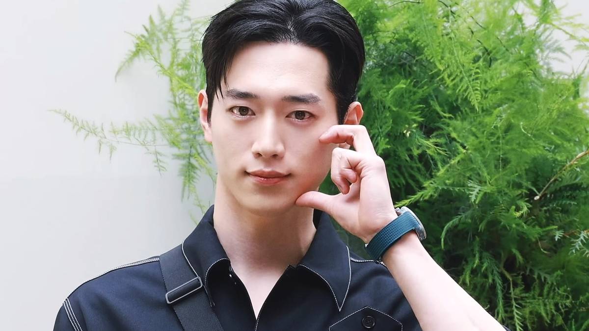 Seo Kang-joon posa de frente num evento de imprensa, com fundo claro