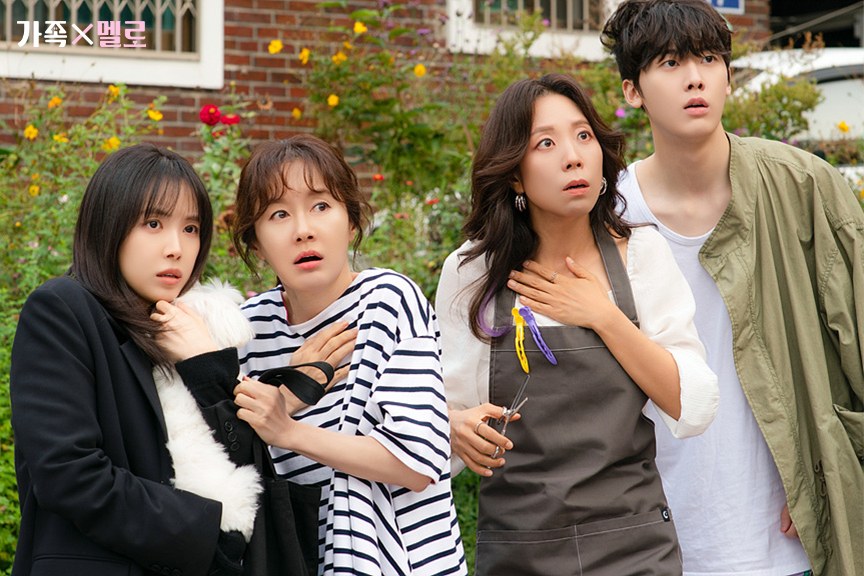 Son Na-eun segurando um cachorro branco, Kim Ji-soo de camiseta listrada, uma moradora de avental e Yoon San-ha olham assustados para o mesmo ponto num jardim